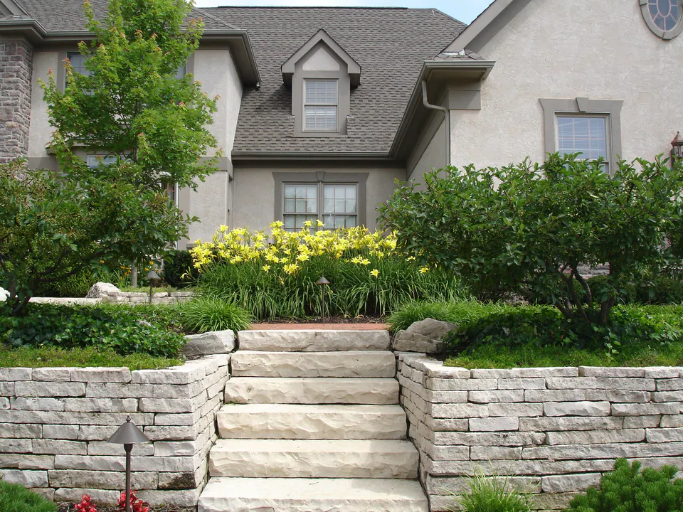 Two limestone retaining walls with wide stone steps between them leading up a front slope